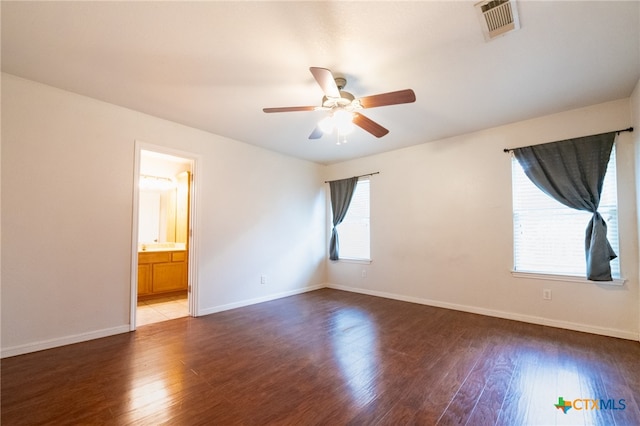 unfurnished room featuring a wealth of natural light, dark hardwood / wood-style floors, and ceiling fan