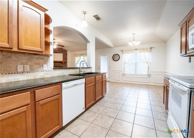 kitchen featuring sink, dark stone countertops, backsplash, hanging light fixtures, and white appliances