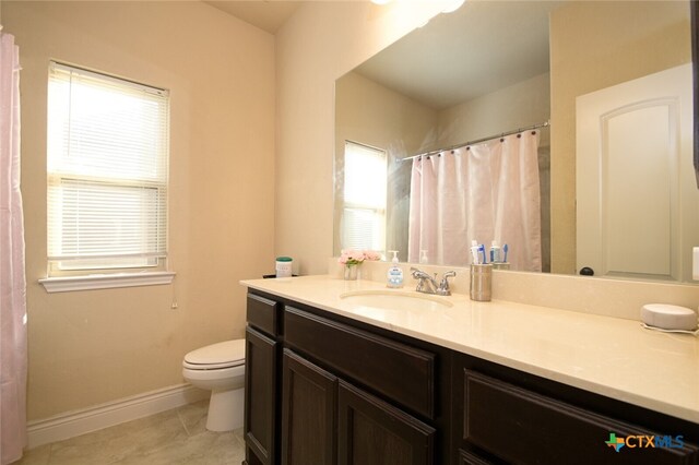 bathroom featuring tile patterned flooring, vanity, a healthy amount of sunlight, and toilet