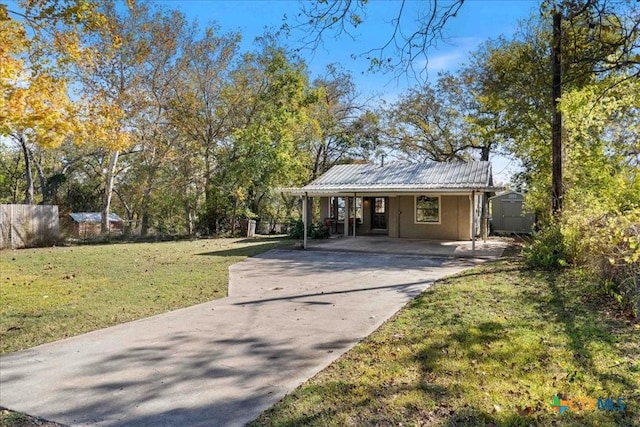 view of front of house with a front yard, a carport, and a storage shed