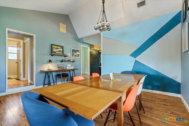 dining room with hardwood / wood-style flooring, a notable chandelier, and lofted ceiling