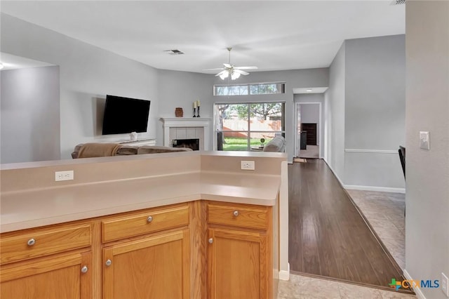 722 Ashland Crk, Victoria, TX 77901 - kitchen with ceiling fan, open floor plan, light countertops, and a tiled fireplace