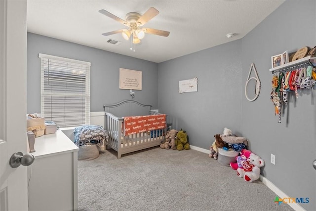 bedroom with a nursery area, ceiling fan, and carpet