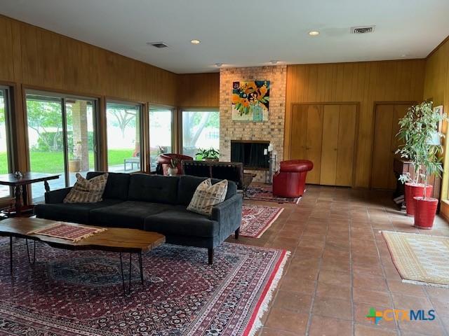 6014 Country Club Dr, Victoria, TX 77904 - tiled living area with visible vents, wood walls, a brick fireplace, and recessed lighting