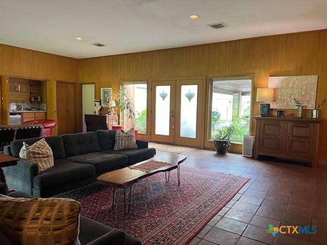 6014 Country Club Dr, Victoria, TX 77904 - living room with wooden walls, visible vents, and a healthy amount of sunlight