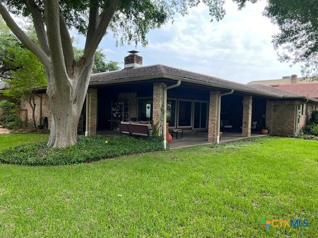 6014 Country Club Dr, Victoria, TX 77904 - back of house featuring a lawn, a patio, and a chimney