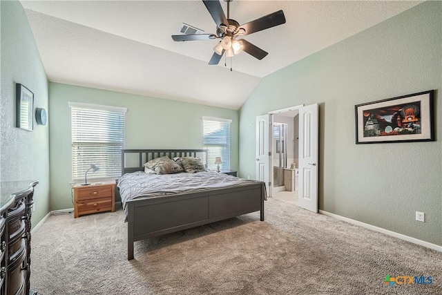 carpeted bedroom featuring ceiling fan, vaulted ceiling, ensuite bathroom, and multiple windows