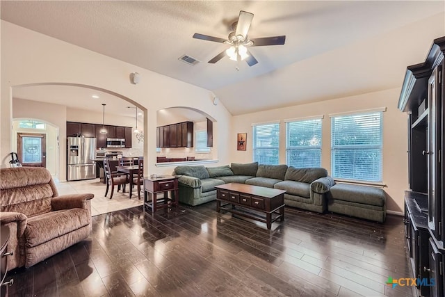 living room featuring vaulted ceiling, ceiling fan, and dark wood-type flooring