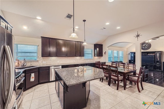 kitchen featuring a wealth of natural light, a center island, stainless steel appliances, pendant lighting, and vaulted ceiling