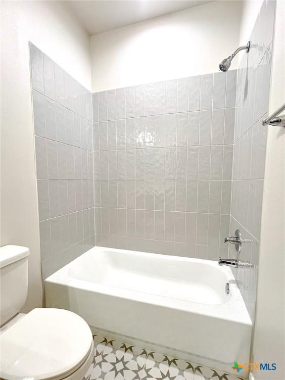 bathroom featuring toilet and tiled shower / bath