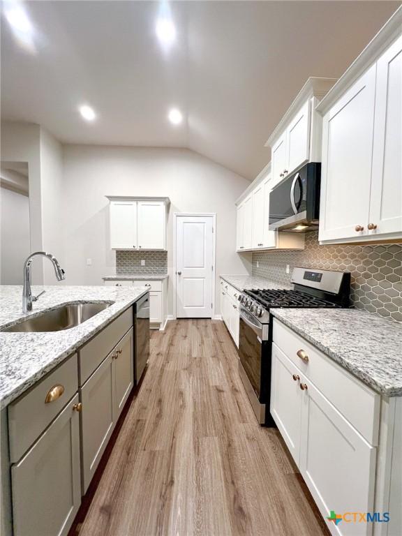 kitchen featuring backsplash, white cabinetry, sink, and appliances with stainless steel finishes