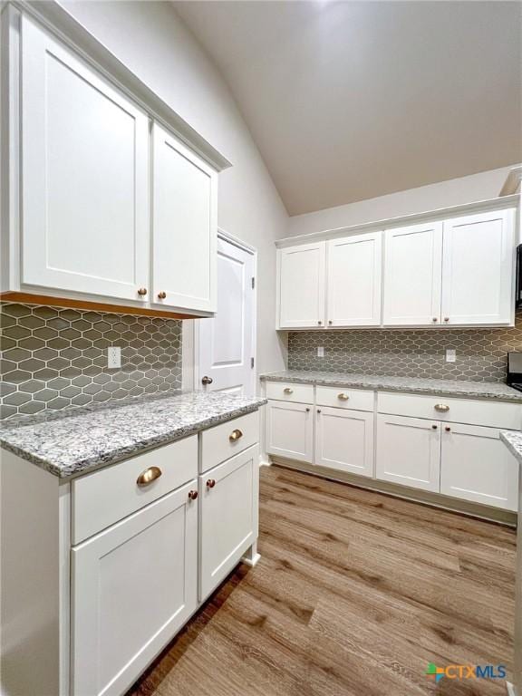 kitchen featuring backsplash, white cabinetry, and light wood-type flooring