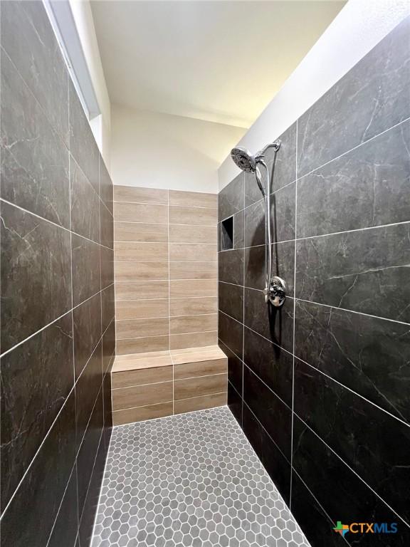 bathroom with tile patterned flooring and a tile shower