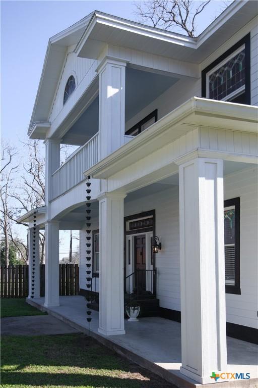 view of exterior entry with covered porch, board and batten siding, and a balcony