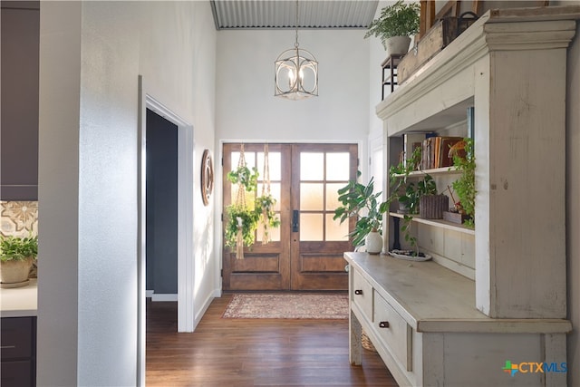 entryway featuring dark wood-type flooring, an inviting chandelier, and french doors