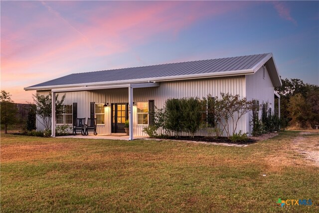 back house at dusk featuring a yard