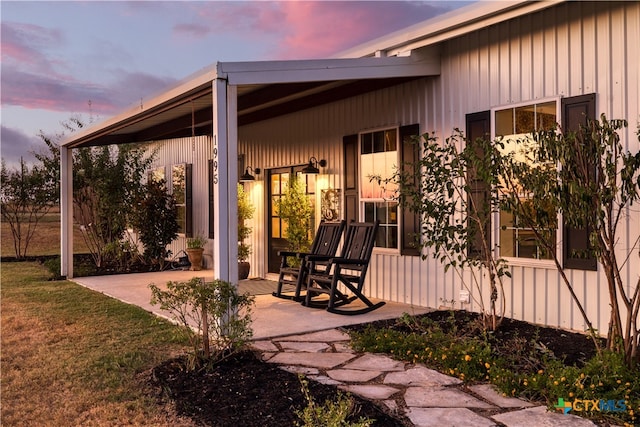 patio terrace at dusk featuring a lawn