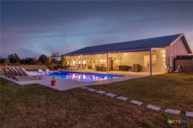 pool at dusk with a yard and a patio area