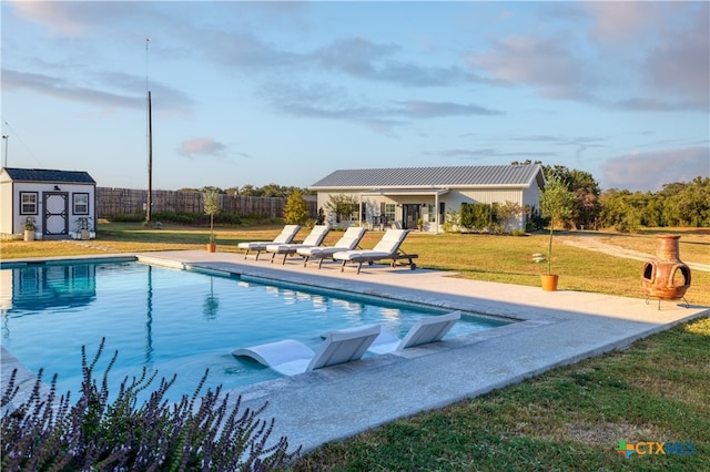 view of pool featuring a patio, a yard, and a shed