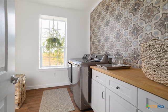 clothes washing area featuring light wood-type flooring, cabinets, and washing machine and clothes dryer