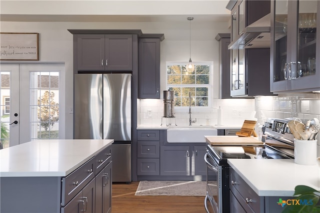 kitchen featuring sink, appliances with stainless steel finishes, backsplash, decorative light fixtures, and dark wood-type flooring