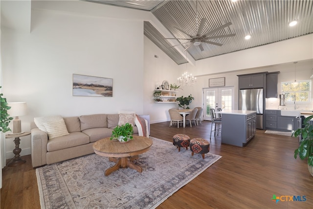 living room with high vaulted ceiling, ceiling fan with notable chandelier, dark hardwood / wood-style floors, and sink