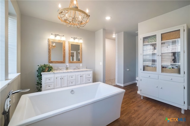 bathroom with a notable chandelier, hardwood / wood-style flooring, vanity, and a bath