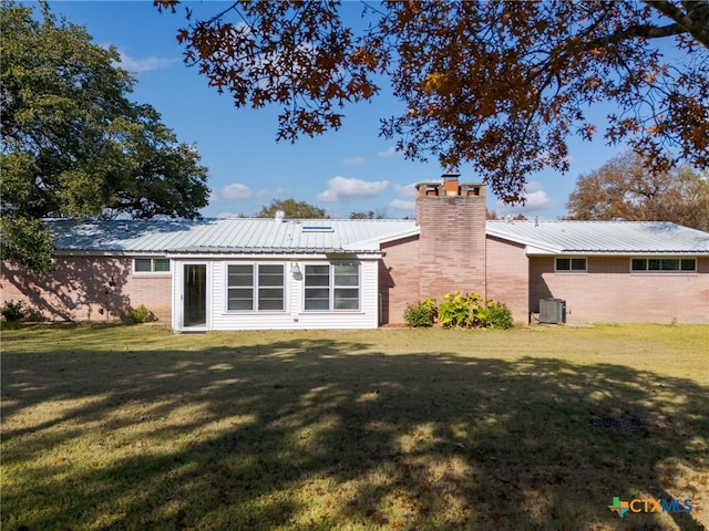 rear view of property featuring cooling unit and a yard