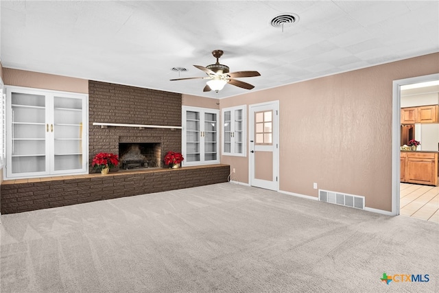 unfurnished living room featuring light colored carpet, a brick fireplace, and ceiling fan