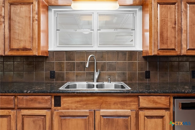 kitchen featuring backsplash, dark stone countertops, and sink