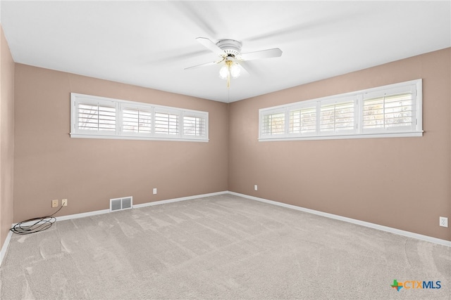 carpeted spare room featuring plenty of natural light and ceiling fan