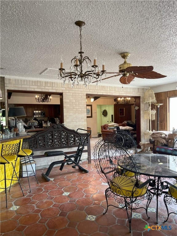 dining area with ceiling fan with notable chandelier and a textured ceiling