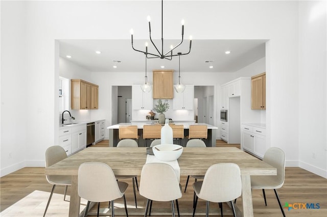 dining area featuring a notable chandelier, sink, and light hardwood / wood-style flooring