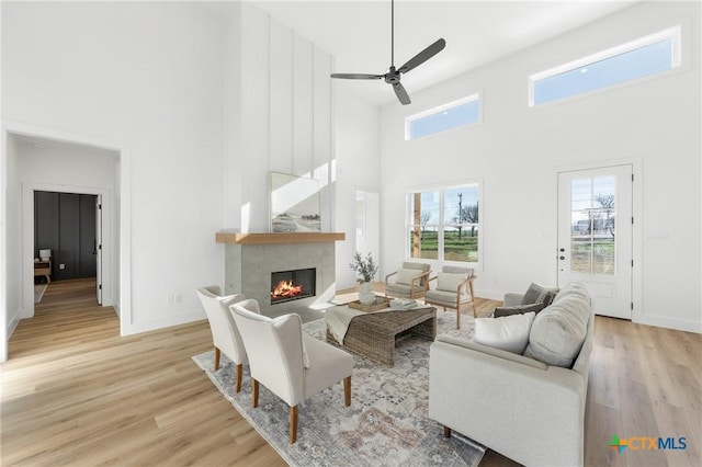 living room with a fireplace, a towering ceiling, and light hardwood / wood-style floors