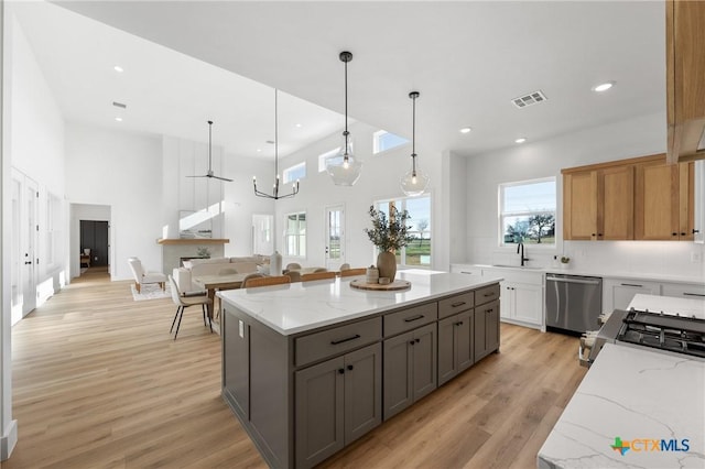 kitchen featuring dishwasher, hanging light fixtures, light hardwood / wood-style flooring, light stone countertops, and tasteful backsplash