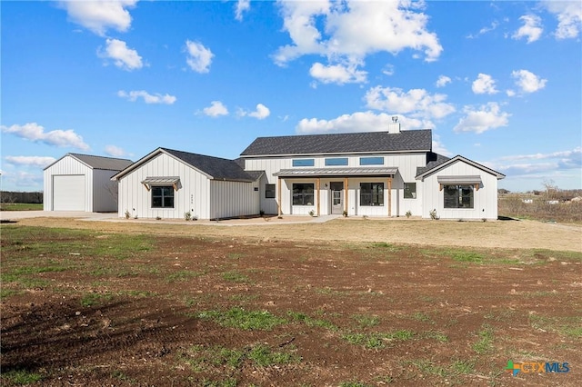 modern farmhouse featuring a garage, a front lawn, and an outdoor structure