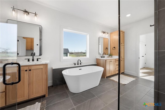 bathroom with tile patterned flooring, vanity, and a tub to relax in