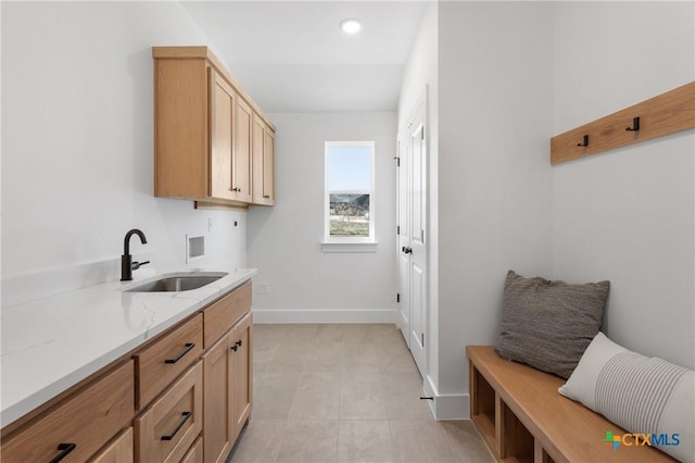 kitchen with light brown cabinets, light stone countertops, and sink