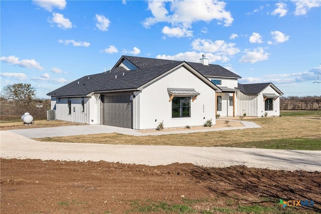 modern farmhouse style home featuring a front yard, a garage, and central air condition unit