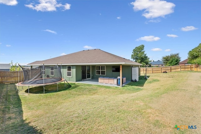 back of house featuring a lawn, a trampoline, and a patio