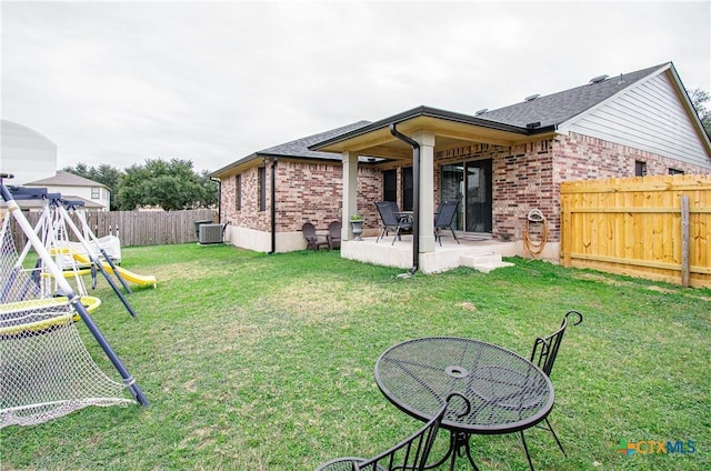 back of house featuring central AC, a patio area, and a lawn