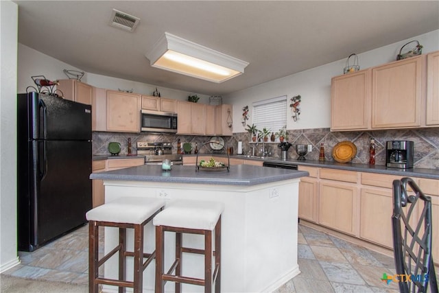 kitchen with a kitchen bar, a center island, tasteful backsplash, and black appliances