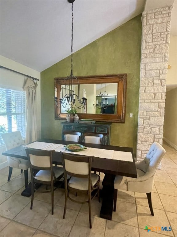 tiled dining space with ornate columns, a chandelier, and lofted ceiling