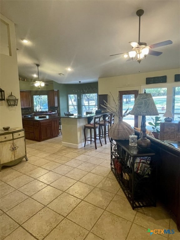 kitchen with a kitchen bar, ceiling fan, and light tile patterned flooring