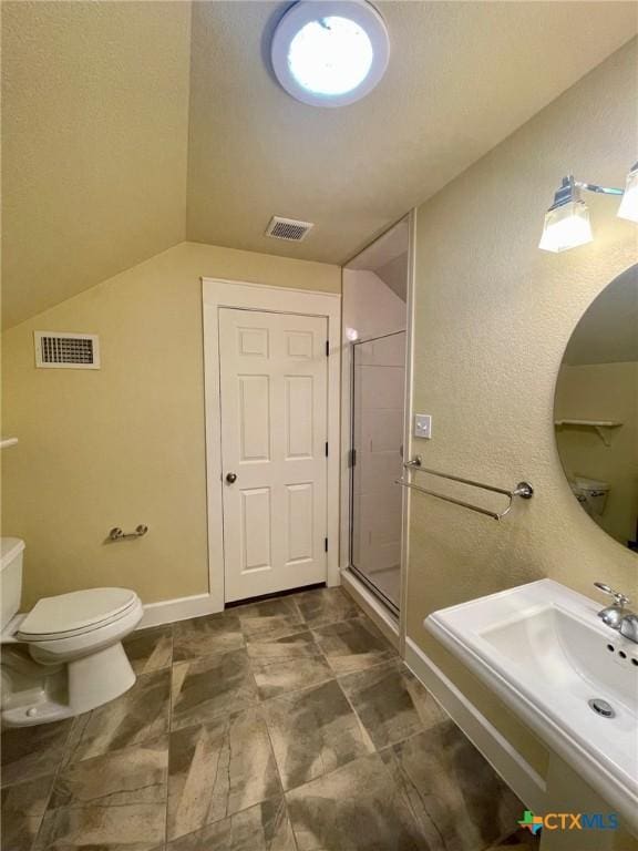 bathroom featuring a shower with door and toilet