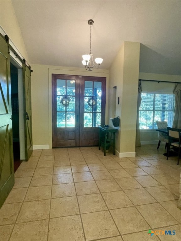 doorway featuring tile patterned flooring, a barn door, lofted ceiling, and a chandelier