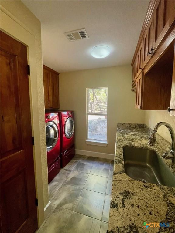 laundry area featuring cabinets, washing machine and dryer, and sink