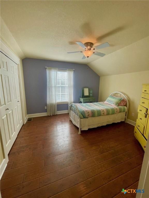 bedroom with dark hardwood / wood-style flooring, ceiling fan, a closet, and vaulted ceiling