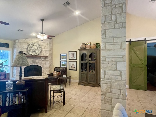 living room with ceiling fan, a barn door, light tile patterned floors, and vaulted ceiling