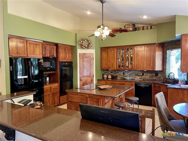 kitchen with black appliances, sink, tasteful backsplash, a kitchen island, and a breakfast bar area